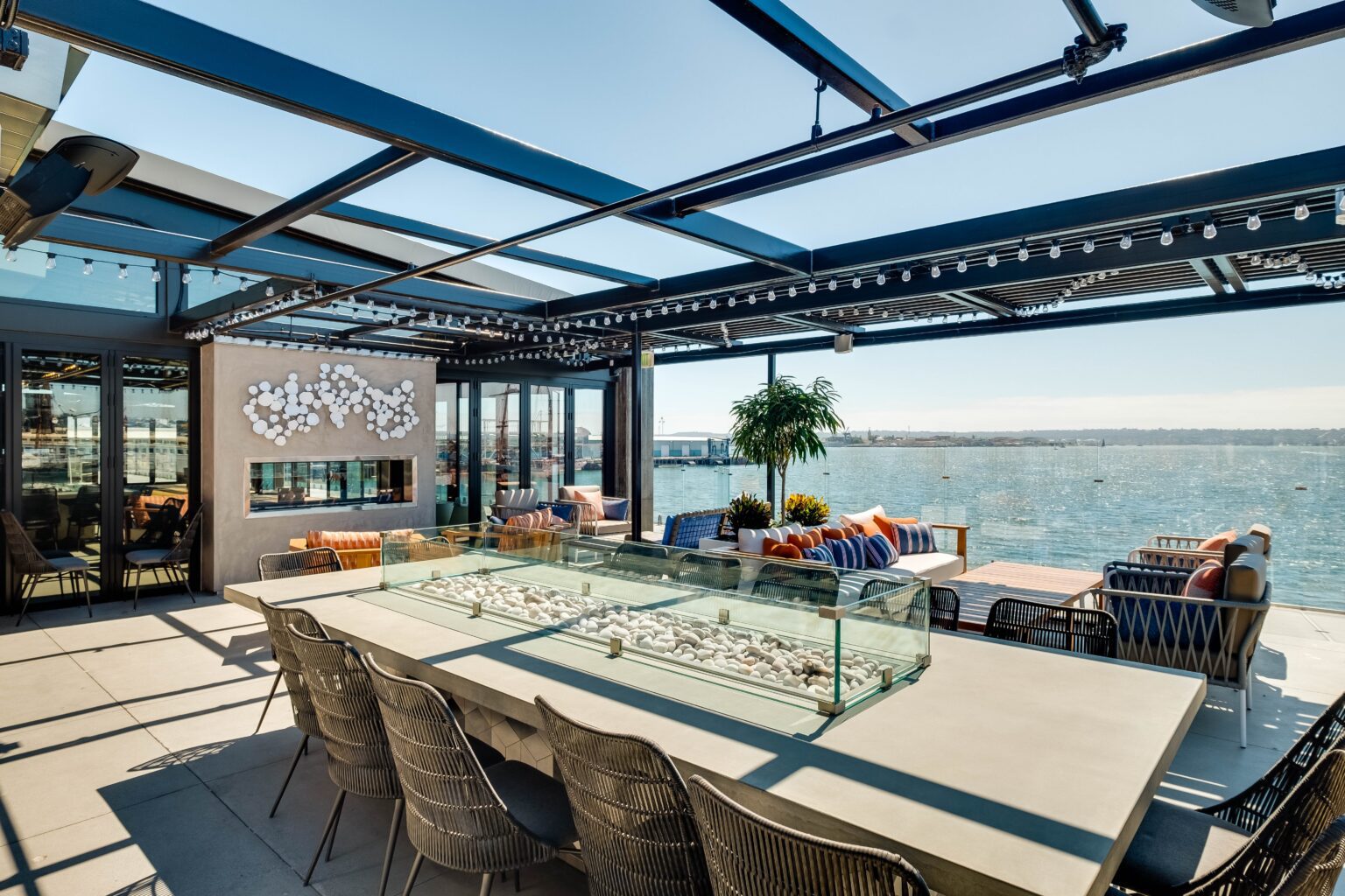 Brigantine rooftop deck with woven Agustin Chairs around a fire table, overlooking the bay